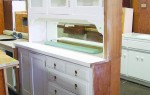 A built-in kitchen cabinet with glass doors on top, four drawers and shelving below