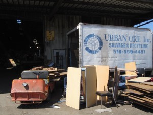 Photo of Urban Ore box truck at the city dump behind a stack of salvaged desks and plywood.